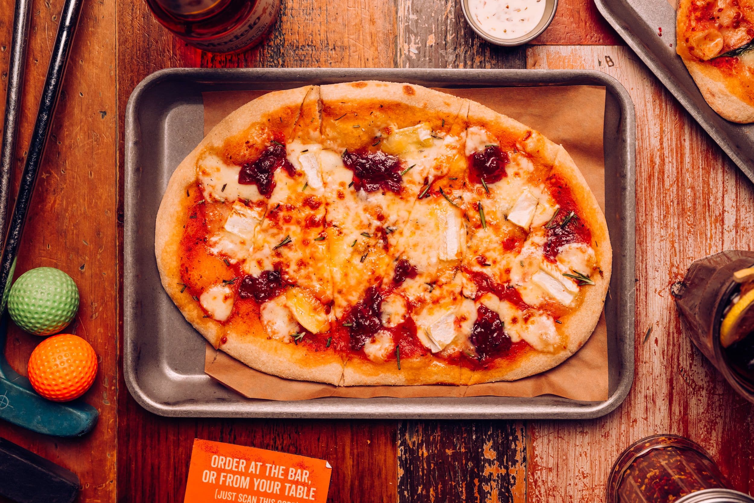 A cracking cranbrie festive pizza displayed on a table at Treetop Golf.